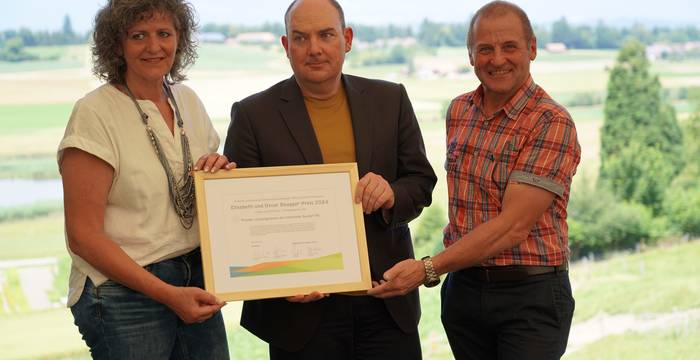 Stiftungsratpräsident der Beugger-Stiftung Jörg Felix übergibt Gemeinderätin Renate Hübscher und Gemeindepräsident Hans Schori stellvertretend für die Gemeinde Seedorf BE den Elisabeth und Oscar Beugger-Preis 2024. Im Hintergrund ist der Lobsigensee zu erkennen. © Richard Geer